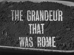 title card: white all caps text reading ‘THE GRANDEUR THAT WAS ROME’ superimposed on dead worms in a box of soil