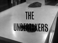 title card: black all caps text reading ‘THE UNDERTAKERS’ superimposed on a cap and a pistol lying on a white table