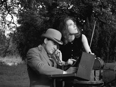 Steed frantically tries to find the frequency of the model bomber while Emma watches the incoming toy aircraft