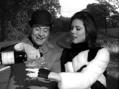 Steed and Emma celebrate with a bottle of champagne while driving off in a golf cart