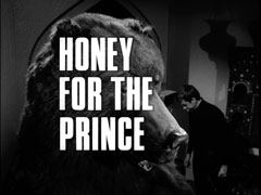 title card: white all caps text reading ‘HONEY FOR THE PRINCE’ superimposed on a stuffed bear standing close-up in the foreground, we can see Vincent standing in the room beyond it on the right