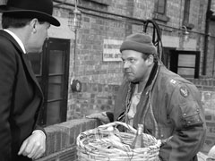 Steed talks to the scrounger, Hickey, as the latter digs through the bins