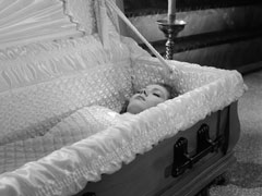 Emma lies in her casket, covered in a quilted cloth