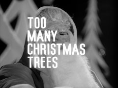 title card: white all caps text reading ‘TOO MANY CHRISTMAS TREES’ superimposed on a man wearing a Santa mask and outfit