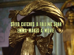 subtitle card: white all caps text with black dropshadow to the left reading ‘STEED CATCHES A FALLING STAR
			EMMA MAKES A MOVIE’ superimposed on the close-up of the statuette
