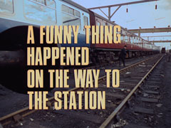 title card: pale yellow all caps text with black dropshadow to the left reading ‘A FUNNY THING HAPPENED ON THE WAY TO THE STATION’ superimposed on a view of Lucas walking up a railway siding beside a stationary train