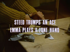 subtitle card: white all caps text with black dropshadow to the left reading ‘STEED TRUMPS AN ACE
			EMMA PLAYS A LONE HAND’ superimposed on the hands feverishly chopped at the remains of the photograph with the scissors