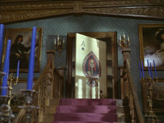 The inside of the house with the ominous Death’s head ace playing card as the door at the top of the stairs