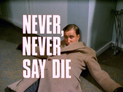 title card: white all caps text with black dropshadow to the left reading ‘NEVER, NEVER SAY DIE’ superimposed on Whittle, who has fainted and fallen against the wall