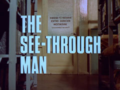 title card: white all caps text with black dropshadow to the left reading 'THE SEE-THROUGH MAN' superimposed on a view from between the shelves of the records office towards the frosted glass door. Painted on the glass and seen reverse is the writing 'MINISTRY OF DEFENCE RECORDS OFFICE INVENTIONS (External Submissions)'