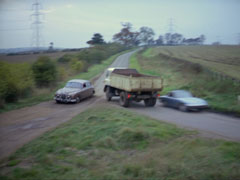 A near collision as a huge lorry passes between Vazin’s Jaguar and Mrs Peel’s Lotus, preventing Vazin from running her off the road