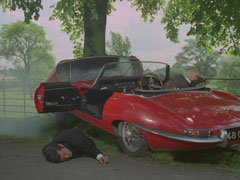 Alex and Carl lie in the wreckage of their crashed E-type Jaguar which has slammed into a tree