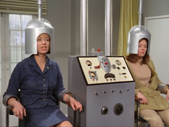 Emma-Lola begs Krelmar to 'switch her back', tricking him by saying that she is Lola - both women sit in the mind transfer machine with a metal hood over their heads, the controls of the machine sit between them