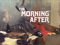title card: white all caps Art Nouveau text reading ‘THE MORNING AFTER’ superimposed on a view inside The Rostarn Trading Company showing Merlin, Tara and Steed passed out from the gas, a large teddy bear on the chair next to the one Merlin is slumped in