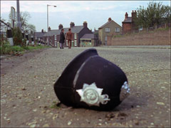 A policeman’s helmet lies abandoned dramatically in the foreground of a deserted street