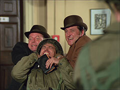 Merlin and Steed grab Sergeant Hearn around the neck with the handcuff chain, forcing him to order his men to drop their weapons
