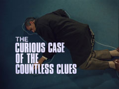 title card: white all caps text reading ‘THE CURIOUS CASE OF THE COUNTLESS CLUES’ superimposed on Dawson lying inside the chalk outline on the carpet