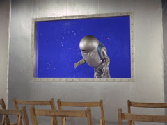 The inflated astronaut sails through the blue room visible through the window