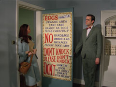 Rugman opens the door to Tara and makes sure she’s read the Victorian circus poster styled sign which fills the entire door: ‘EGGS FRAGILE, FRAGILE AREA TAKE CARE, HANDLE AS EGGS, TREAD CAREFULLY, NO HANDBAGS, UMBRELLAS, PACKAGES, PLEASE TAKE CARE, DON’T KNOCK, PLEASE DON’T KNOCK, DONT’T SLAM THE DOOR, TALK LOUDLY, VIBRATE, EVEN BREATHE’