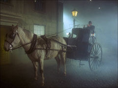 Steed drives a hansom cab through the foggy streets