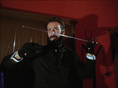 Travers, in his Gaslight Ghoul costume - cape, frock coat, gloves, false beard - prepares to throw a sword stick
