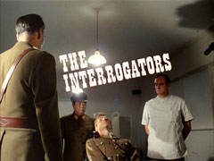 title card: white all caps ornate text slightly askew reading ‘THE INTERROGATORS’ superimposed on Caspar, sitting in a chair under a bright light surrounded by Mannering, Soo and Blackie who are interrogating him