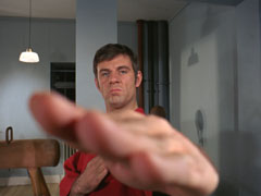 Captain Tim, in a red gi, practices his karate, his hand nearly hitting the camera in extremely foreshortened perspective