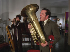 Steed and Tara try the different instruments, trying to find the right note to unlock the suitcase
