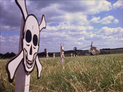Kafka’s helicopter lands in the field near the skull and crossbones signs marking the minefield