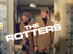 title card: white all caps text reading ‘THE ROTTERS’ askew by 30 degrees counter-clockwise and superimposed on Kenneth and George smiling at the now-disintegrated door