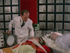 Tara and Kartovski lie on two gurneys (he lies on ice) in Constantine’s red, white and black laboratory, both attached to the mind transferring machine as Dr. Constantine gloats at Tara