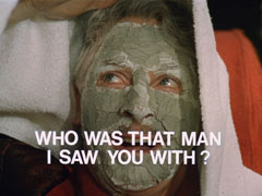 title card: white all caps text reading ‘WHO WAS THAT MAN I SAW YOU WITH?’ superimposed on Zaroff’s face covered in a green clay facepack, a towel over his head