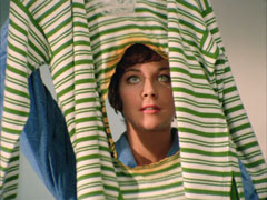 Tara hold her green and white striped suit up and peers through the large round hole where the back has been burnt through